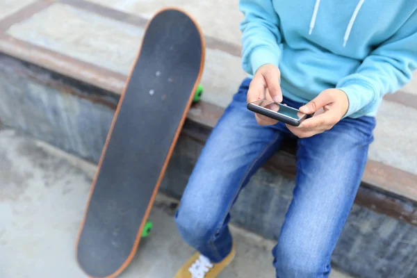 Junge Skateboarder nutzen Smartphone — Stockfoto