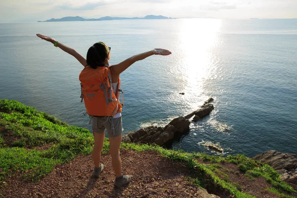 Mujer con mochila de pie en la montaña junto al mar — Foto de Stock