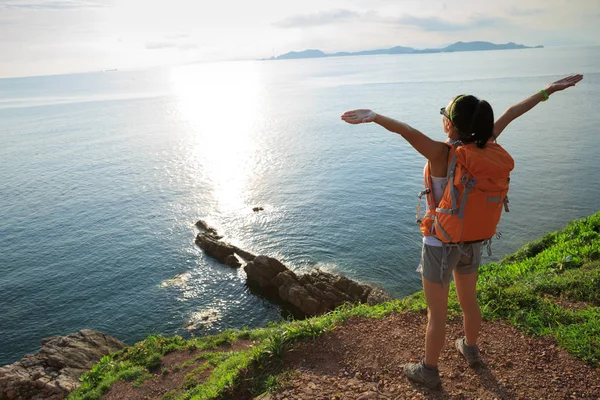 Mulher com mochila em pé na montanha à beira-mar — Fotografia de Stock