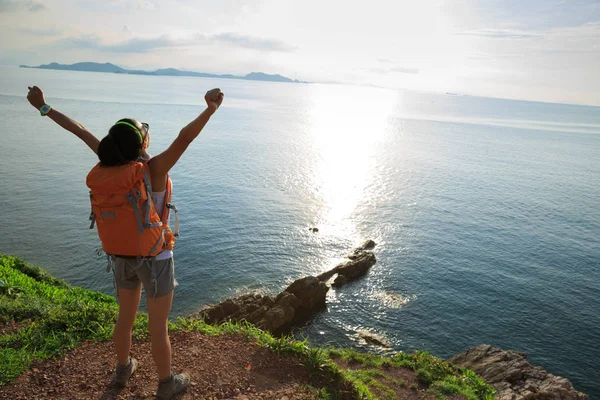 Mujer con mochila de pie en la montaña junto al mar — Foto de Stock