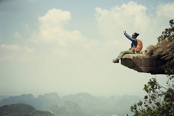 Mulher sentada no penhasco do pico da montanha — Fotografia de Stock