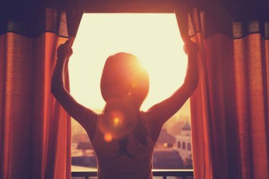 Perdeleri açan genç kadın.