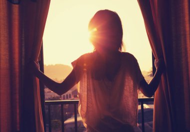 Perdeleri açan genç kadın.