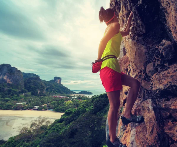 Vrouw klimmen aan zee klif — Stockfoto