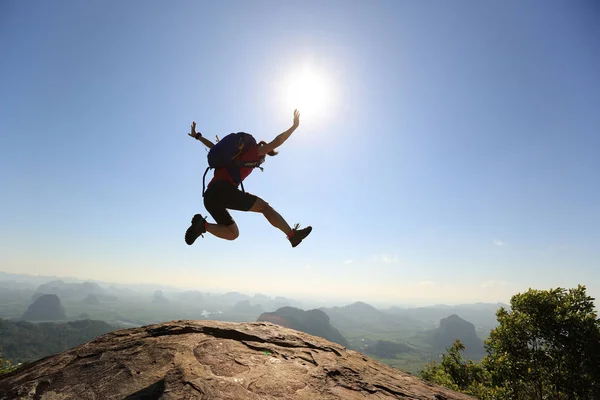 Молодая женщина прыгает на вершину горы — стоковое фото