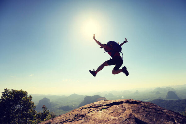 young woman jumping on mountain peak