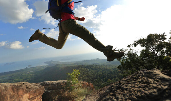 young woman jumping on mountain peak