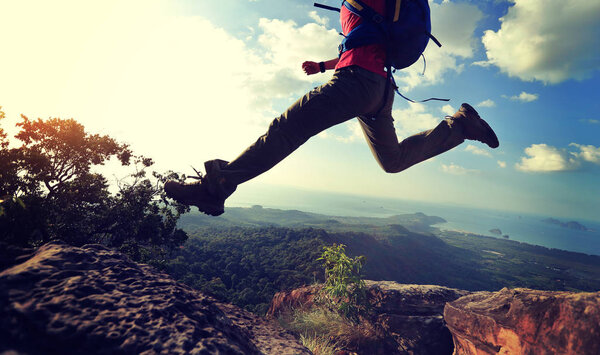 young woman jumping on mountain peak