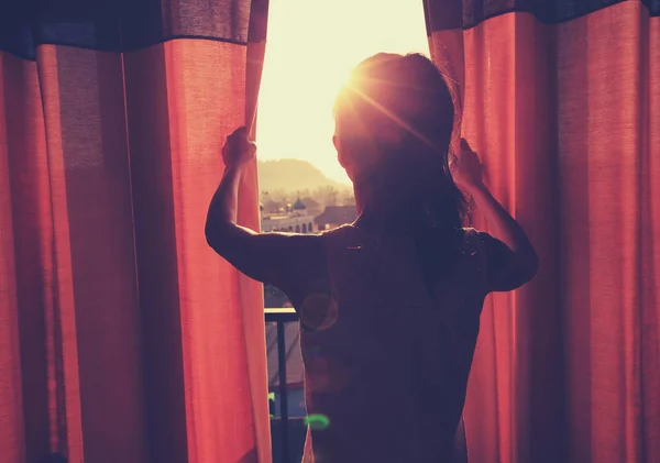 Mujer joven abriendo cortinas — Foto de Stock