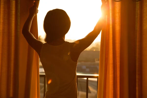 Junge Frau öffnet Vorhänge — Stockfoto