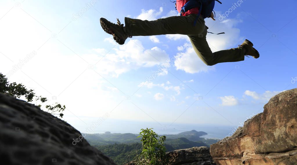 young woman jumping over precipice
