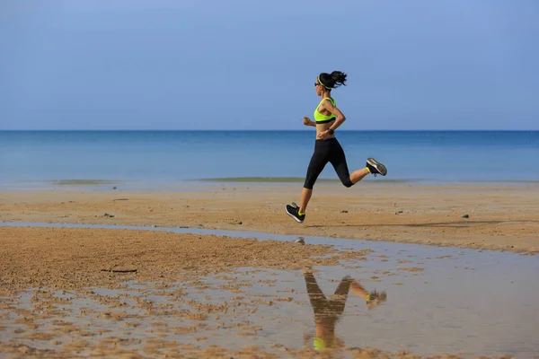 Sportieve jonge vrouw lopen op strand — Stockfoto