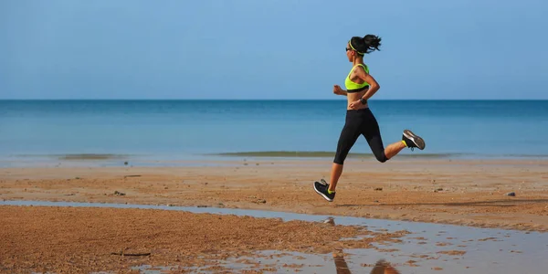 Sportieve jonge vrouw lopen op strand — Stockfoto