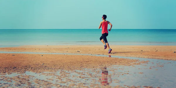 Sportos fiatal nő fut beach — Stock Fotó