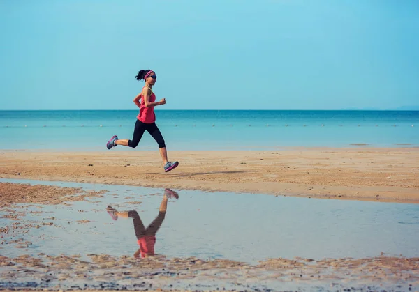 Jeune femme sportive courant sur la plage — Photo