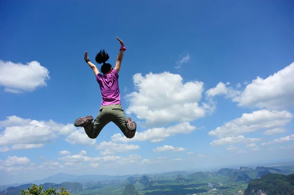 Jovem mulher pulando no pico da montanha — Fotografia de Stock