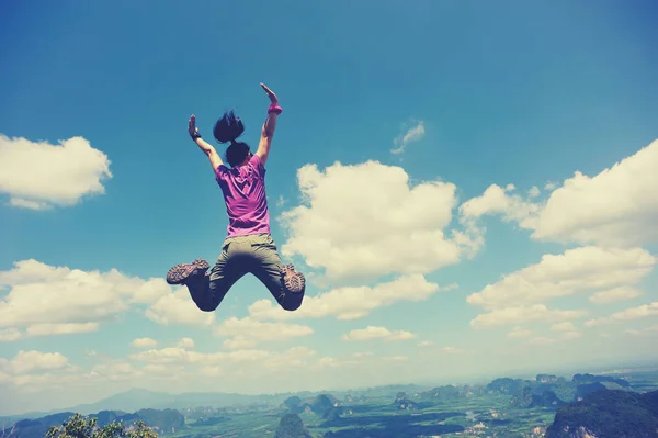 Junge Frau springt auf Berggipfel — Stockfoto