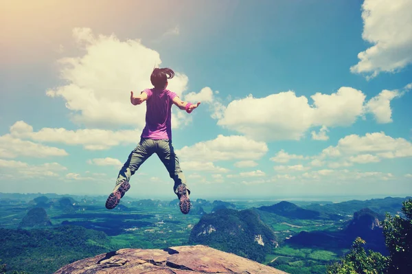 Junge Frau springt auf Berggipfel — Stockfoto