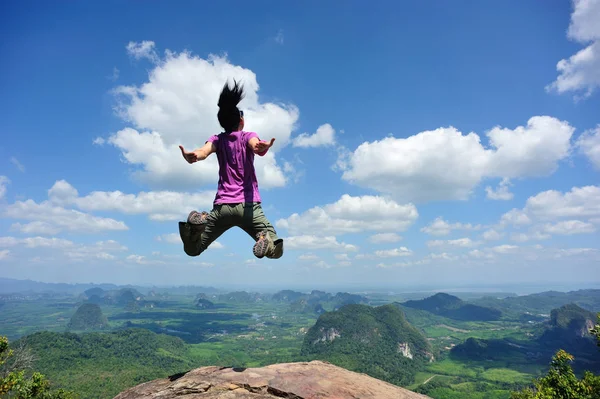 Jovem mulher pulando no pico da montanha — Fotografia de Stock