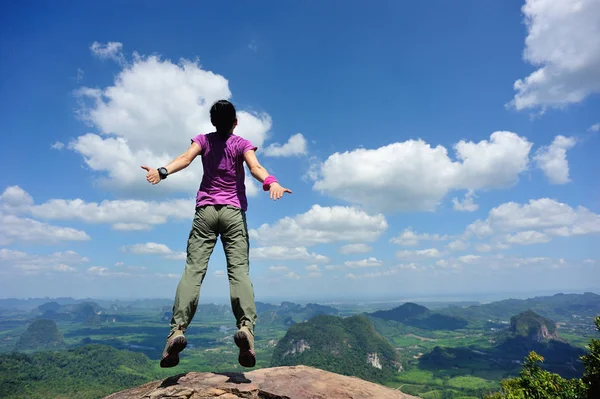 Jovem mulher pulando no pico da montanha — Fotografia de Stock