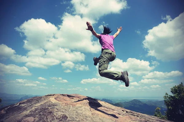 Jovem mulher pulando no pico da montanha — Fotografia de Stock
