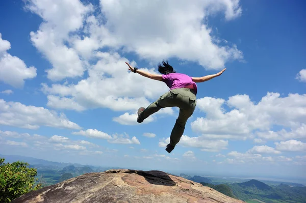 Young woman jumping on mountain peak — Stock Photo, Image