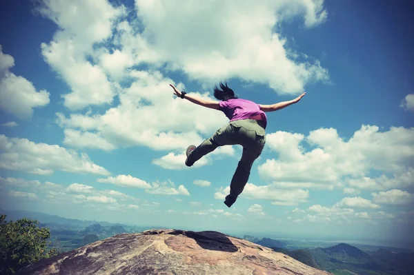 Junge Frau springt auf Berggipfel — Stockfoto