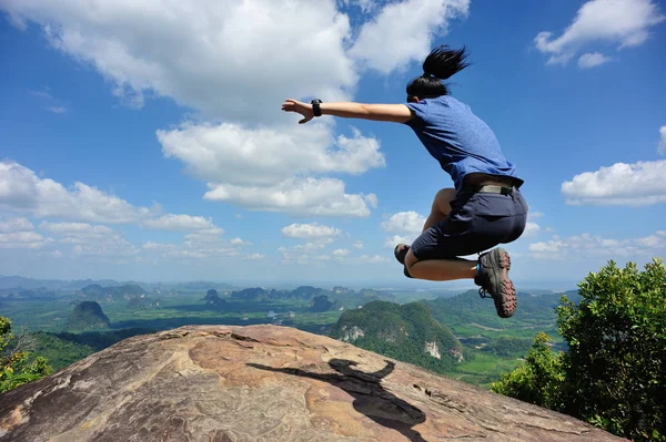 Jovem mulher pulando no pico da montanha — Fotografia de Stock