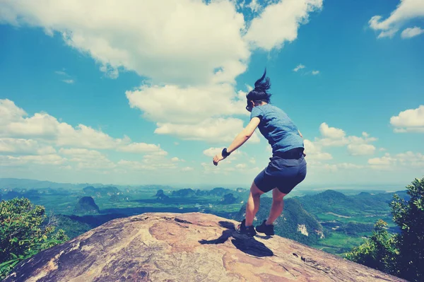 Young woman jumping on mountain peak — Stock Photo, Image