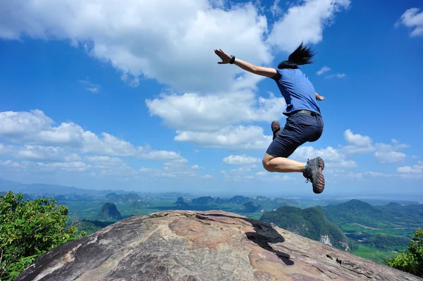 Mujer joven saltando en el pico de la montaña — Foto de Stock