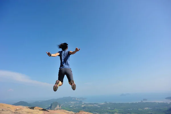 Woman jumping on mountain peak — Stock Photo, Image