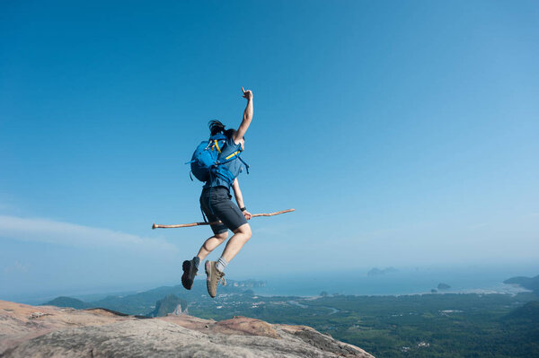 woman jumping on mountain peak 