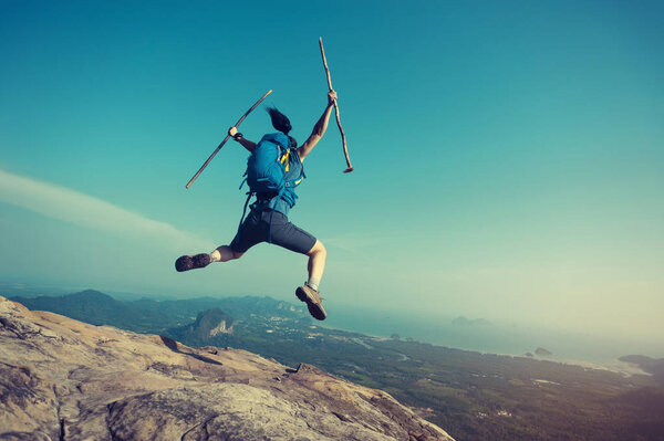 woman jumping on mountain peak 