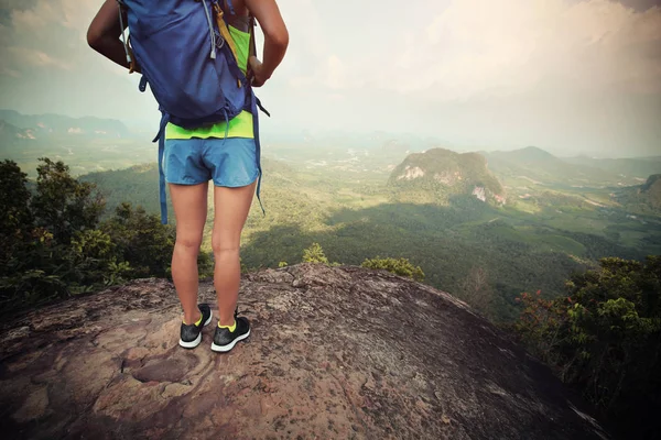 Женщина с рюкзаком стоит на вершине горы — стоковое фото