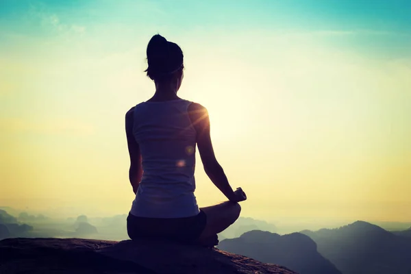 Jovem mulher meditando no pico da montanha — Fotografia de Stock