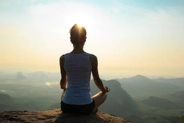 Mujer meditando en el pico de la montaña — Foto de Stock