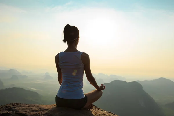 Mujer meditando en el pico de la montaña — Foto de Stock