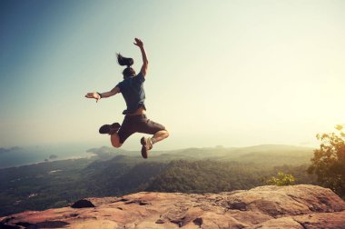woman jumping on mountain peak  clipart