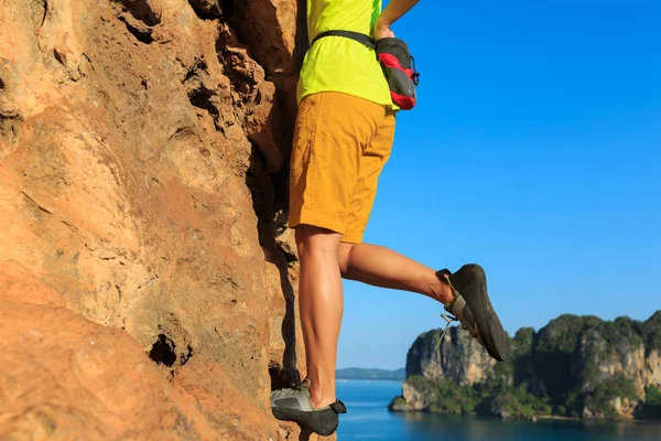 Junge Frau klettert an Klippe am Meer — Stockfoto