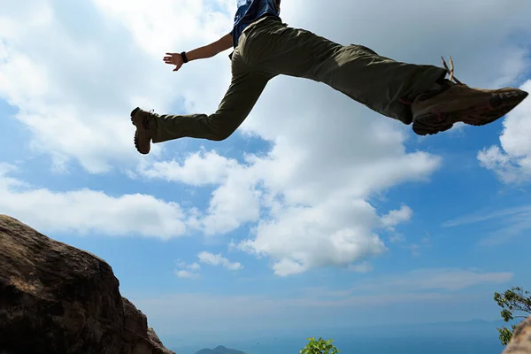 Mujer joven saltando sobre el precipicio — Foto de Stock
