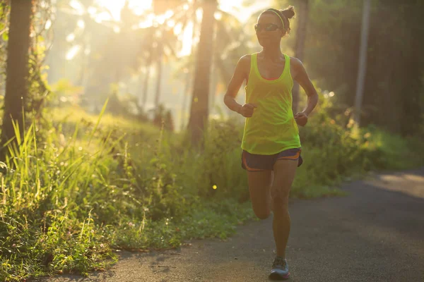 Mujer joven corriendo por sendero forestal —  Fotos de Stock