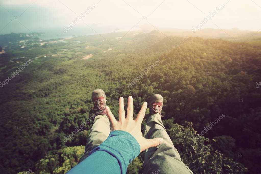 hiker sitting on edge of mountain peak