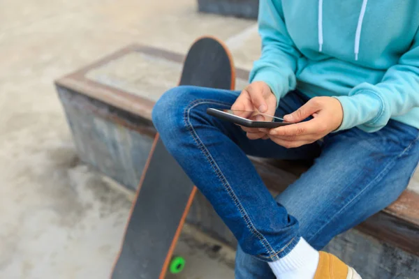 Giovane skateboarder utilizzando smartphone — Foto Stock