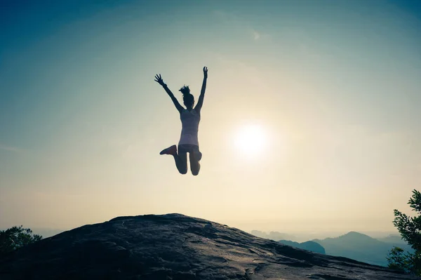 Jonge vrouw springen op de bergtop — Stockfoto