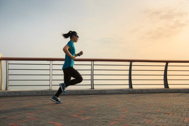  Genç kadın deniz kenarında koşuyor.
