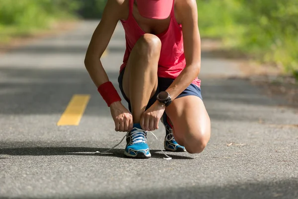 Mulher amarrando cadarço antes de correr — Fotografia de Stock