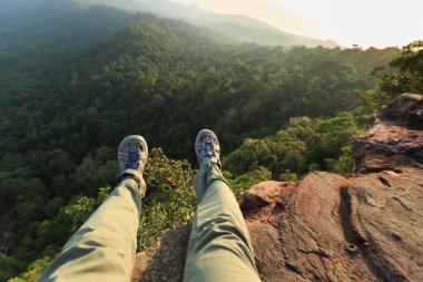Dağ cliff üzerinde oturan genç kadın