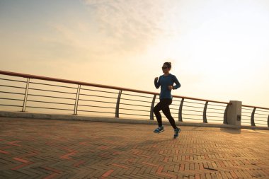 Genç kadın deniz kenarında koşuyor.