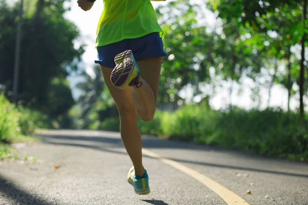 Jeune femme sportive qui court sur le sentier forestier — Photo