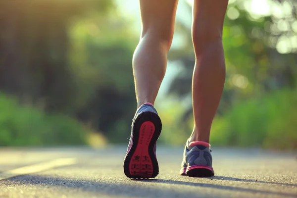 Sportliche junge Frau läuft auf Waldweg — Stockfoto